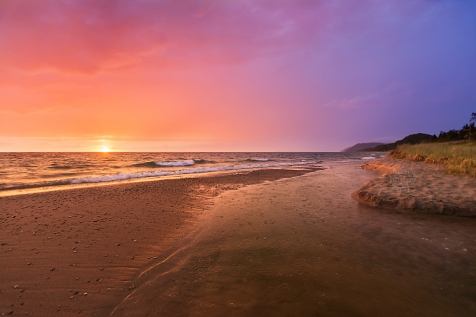 Photo: A glowing sunset sparkles over a creek flowing into Lake Michigan