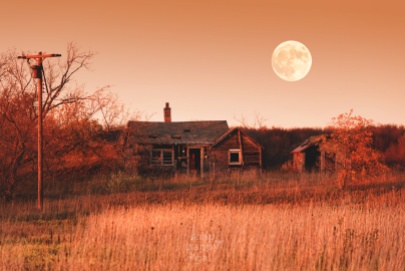 A full moon looms over a decaying Leelanau homestead in red sunset light