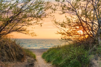Photo: A peachy sunset beckons down a sandy path to blue Lake Michigan waters