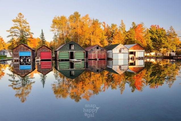 A collection of colorful boathouses form perfect reflections in the Torch River near Alden, Michigan