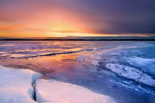 Photo: Glowing sunset reflects off a frozen Torch Lake
