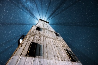 Light rays highlight the starry night sky under the Frankfort Lighthouse