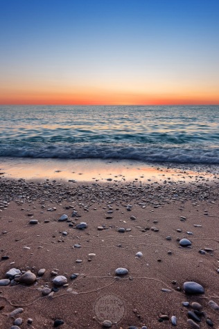 Beach pebbles and sand textures in the afterglow of a blue and gold sunset on Lake Michigan
